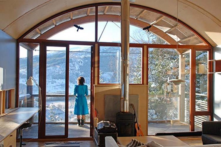 Photo of woman standing at window of DALE artists centre looking out at mountains