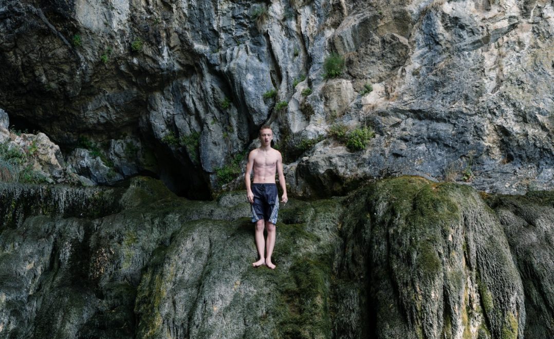 man standing on rocks about to jump into water